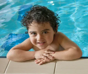 Child smiling while standing in the pool