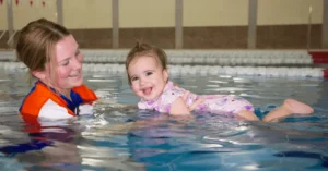 Teacher holding baby in the pool