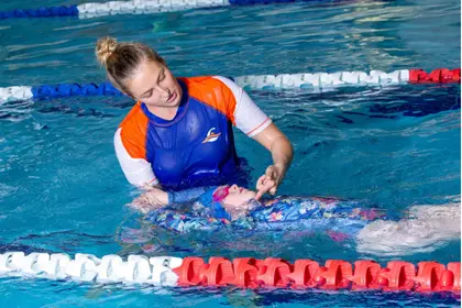 Swim teacher helping student in the water