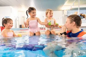 Swim teacher playing with students in water