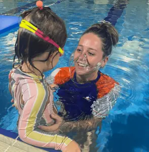 Teacher smiling as a student gets into the pool