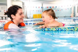 Baby and teacher smiling in the pool together