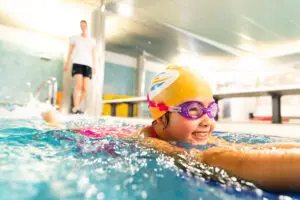 Student smiling and swimming in the pool