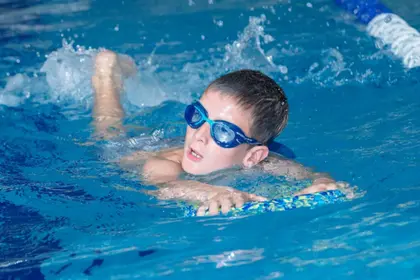 Young boy paddling with kickboard