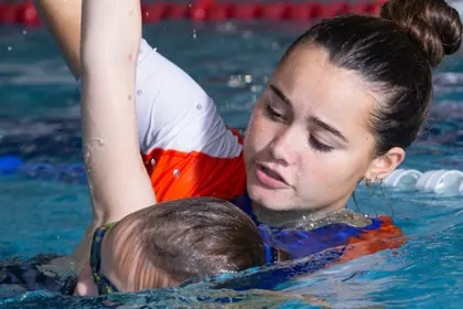 Swim teacher helping a student to swim