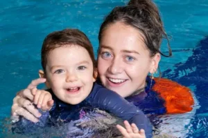 Swim teacher and student smiling in water