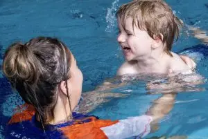 Teacher holding a student up in the water