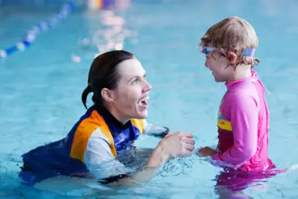 Swim teacher and young girl talking in a pool