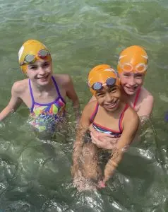 3 Carlile Swimmers smiling in the water