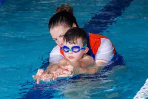 Student being guided in the pool by teacher