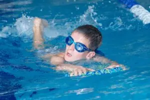 Student swimming with a kickboard in the pool
