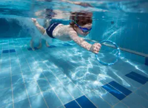 Student reaching for pool ring underwater