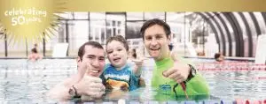 Teacher, dad and student smiling in the pool together
