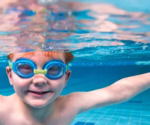 Student smiling underwater with goggles on