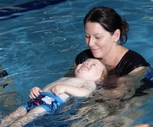 Baby learning how to float with mum in the pool