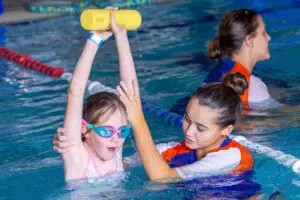 Teacher guiding a student in the pool
