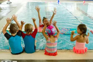 Teacher and students with their hands up in the pool
