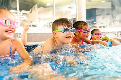 4 young children splashing in the pool