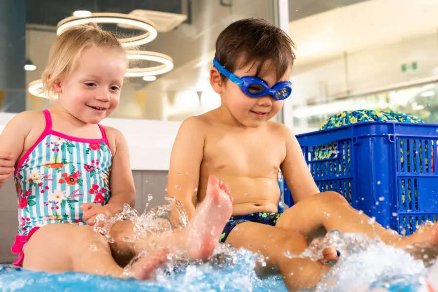 Swim teacher supports a preschool-aged child in an indoor pool as they practise floating and early learn-to-swim skills during a Carlile Preschool lesson.