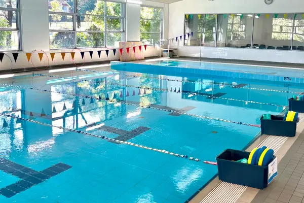 Indoor heated lap pool at Carlile Swim Cherrybrook, showing marked lanes with lane ropes, tiled pool deck, and the bright indoor swim centre.