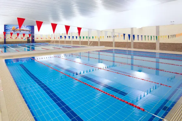 Indoor lap pool at Carlile Swim Lane Cove West, showing marked lanes with lane ropes, tiled pool deck, and the heated indoor facility.