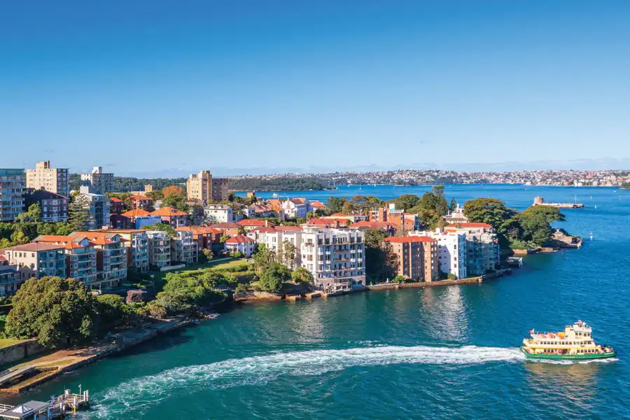 Sydney North Shore skyline across the harbour, with city buildings and water in the foreground.