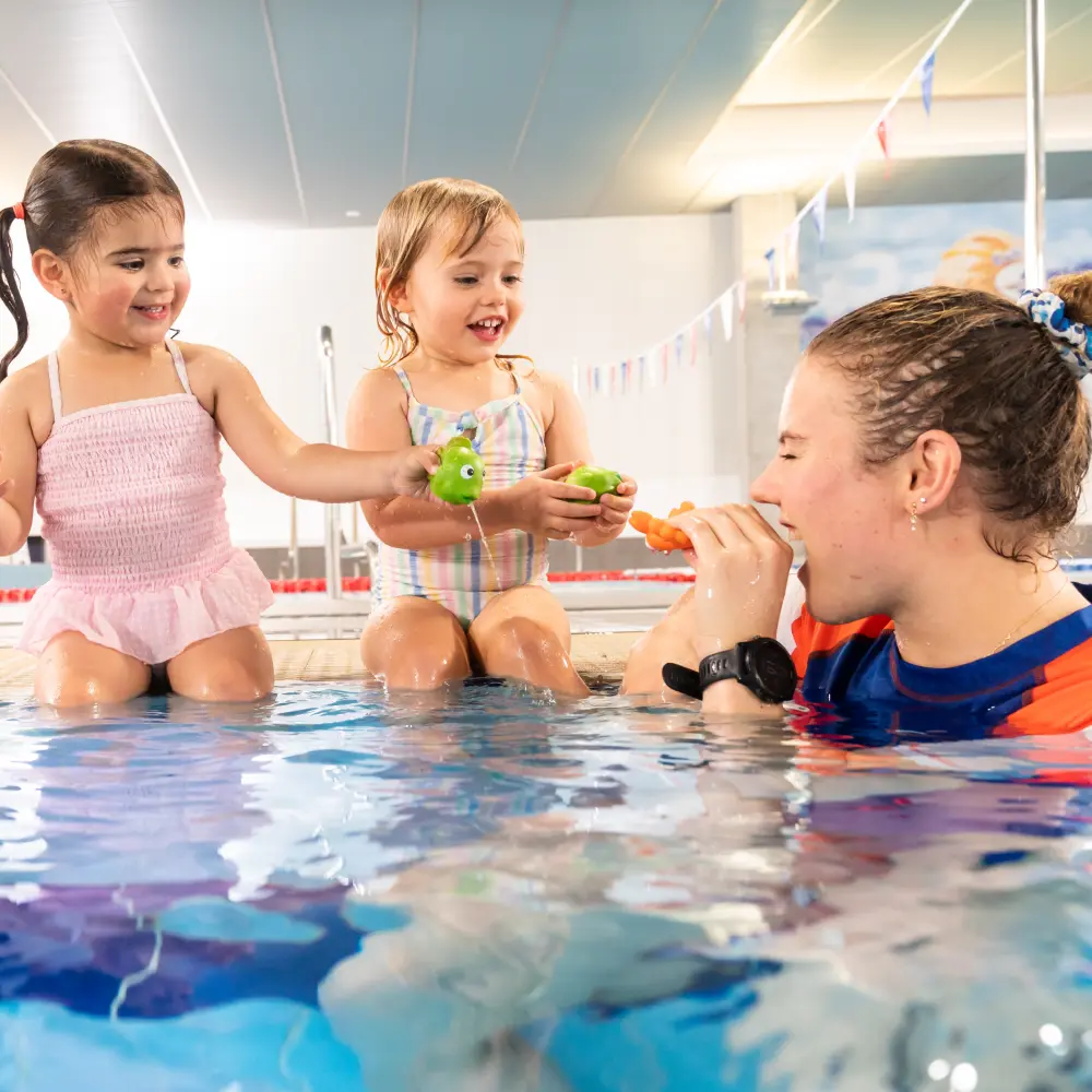 Preschool swim lesson in an indoor pool, showing a Carlile Swim teacher working one-on-one with a young child to build water confidence and early stroke skills.