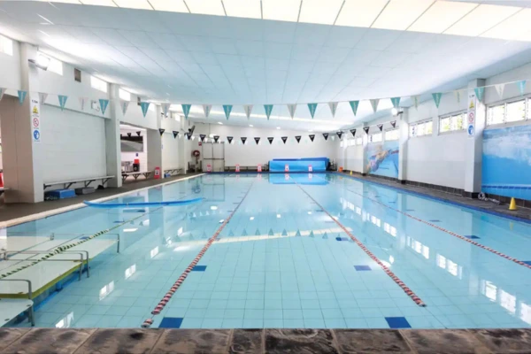 Indoor heated lap pool at Carlile Swim Gumdale, showing marked swim lanes with lane ropes, tiled pool deck, and the bright indoor facility.