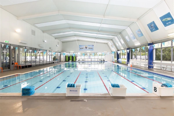 Indoor lap pool at Carlile Swim Paddington, showing marked swim lanes with lane ropes, tiled pool deck, and the heated indoor facility.
